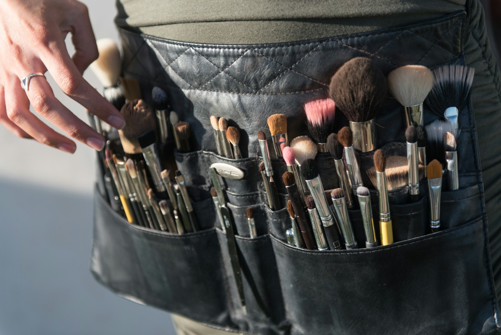 a person is holding a belt full of makeup brushes