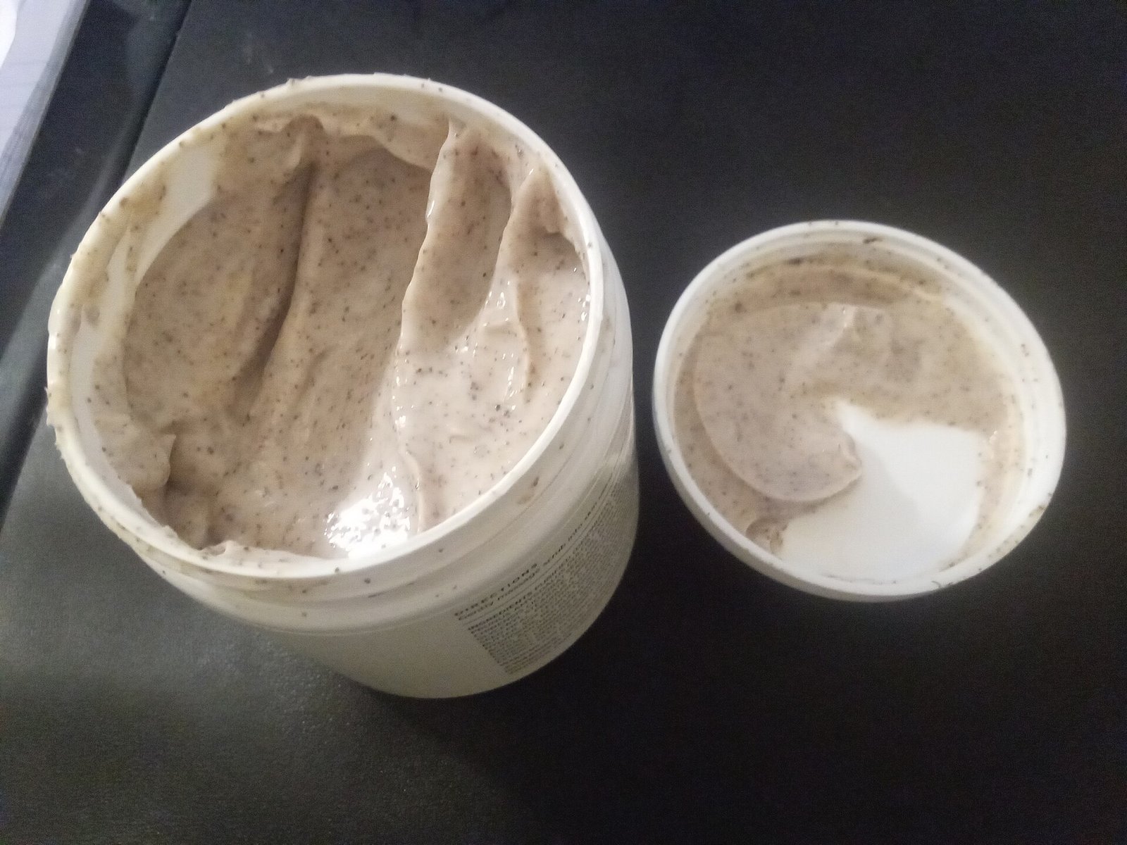 girlook-13 Deux pots ouverts de gommage crème aux fines particules exfoliantes posés sur un fond noir