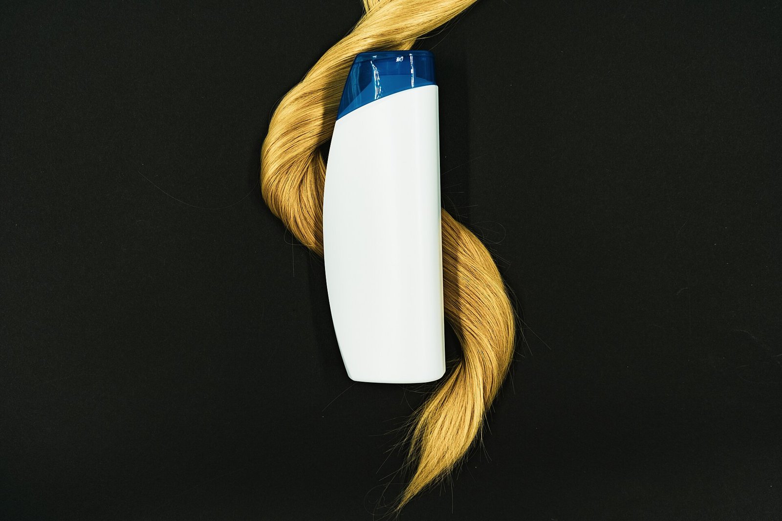 girlook-14 Flacon de soin capillaire entouré d'une mèche de cheveux blonds sur fond noir