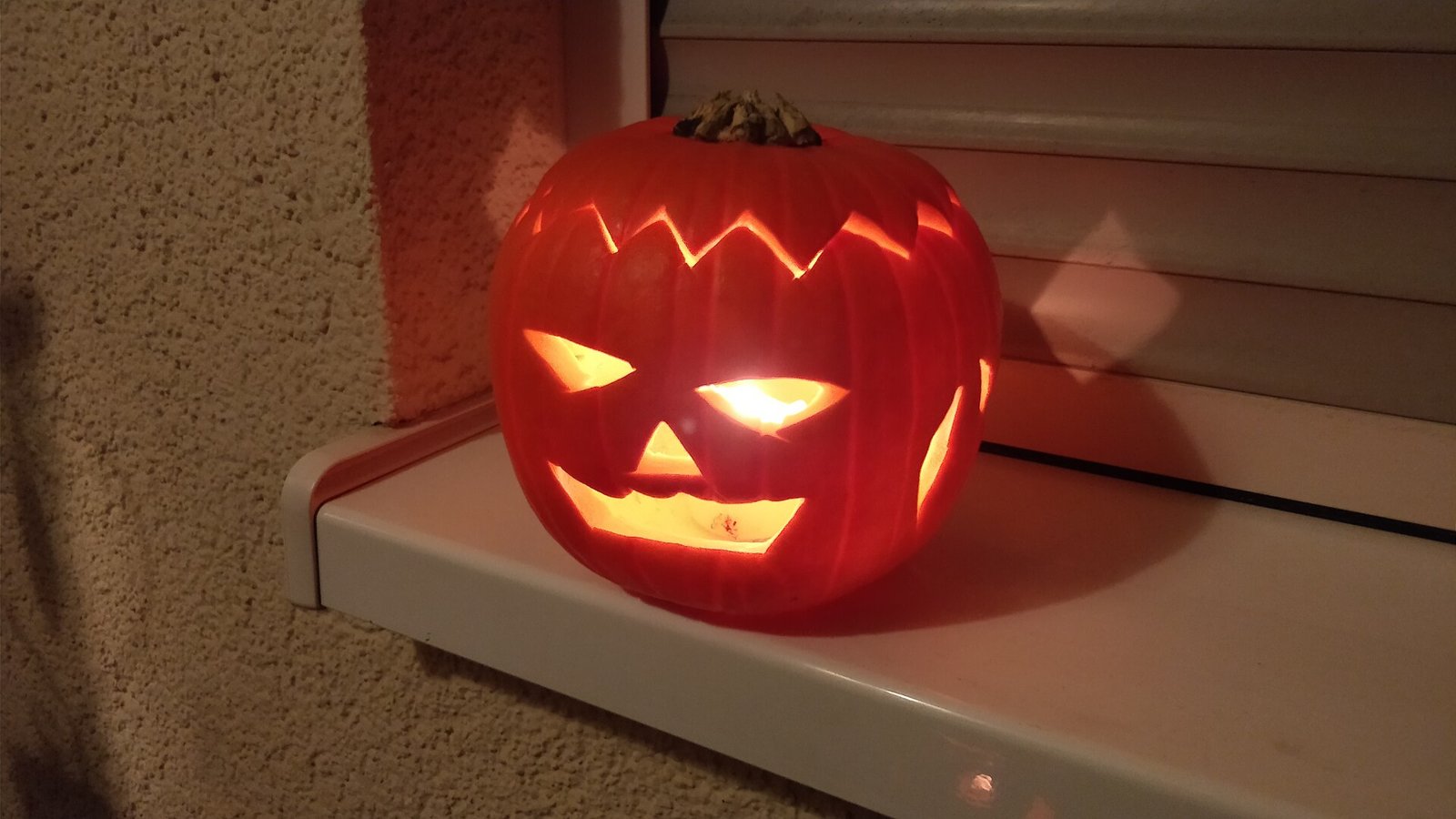 girlook-4 Citrouille d'Halloween sculptée et éclairée de l'intérieur, posée sur un rebord de fenêtre