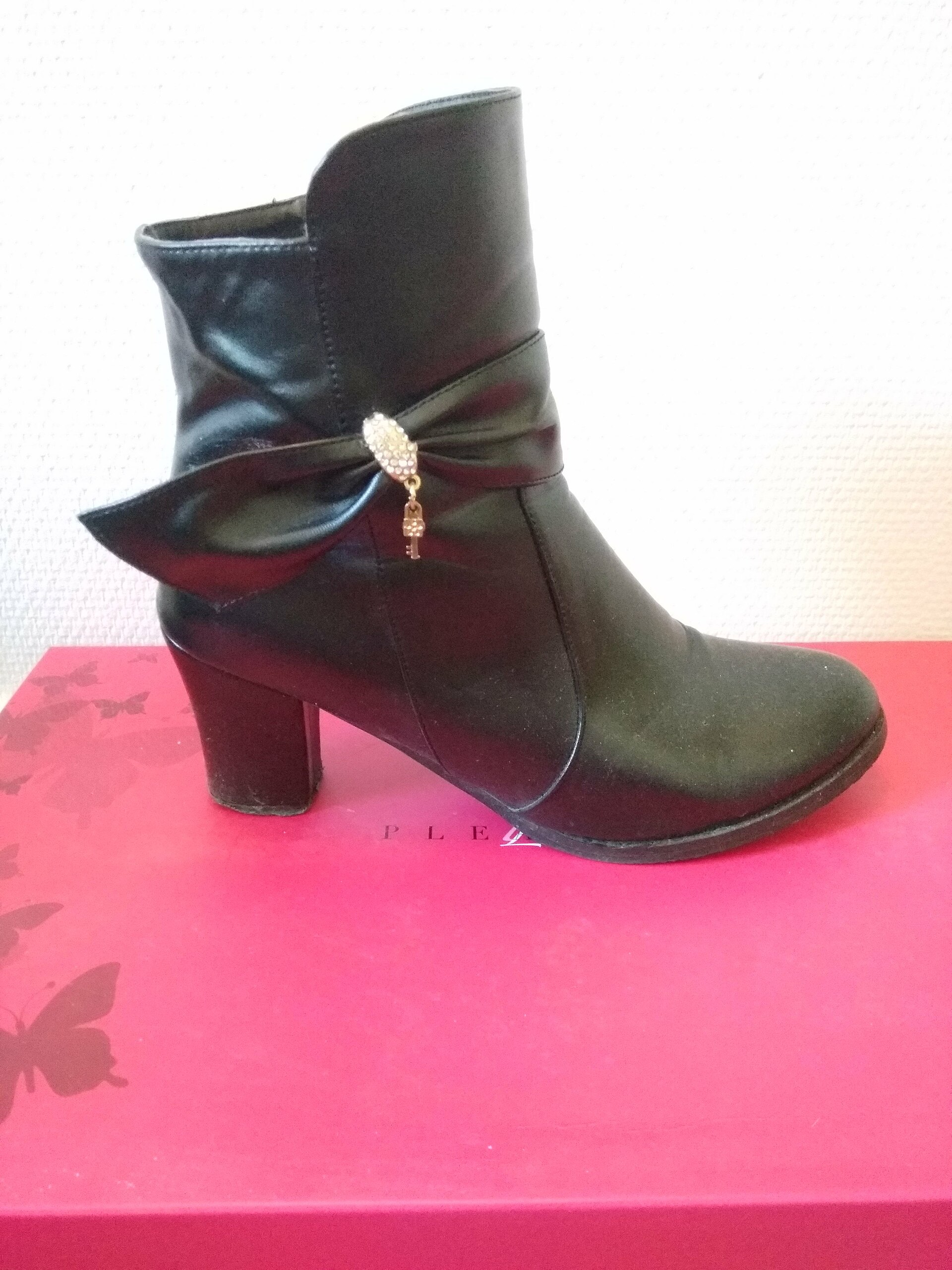 n3-girlook Bottine noire à talon bloc et boucle décorative posée sur une boîte rose